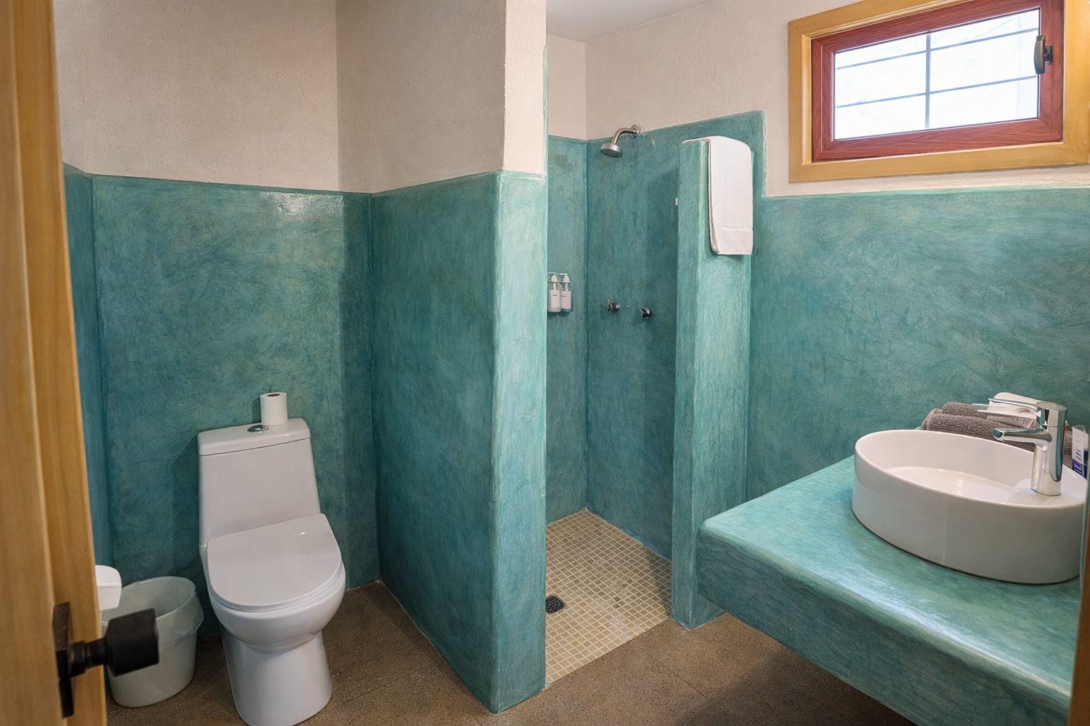 Baño con muros de estuco turquesa, regadera abierta y lavabo de cerámica